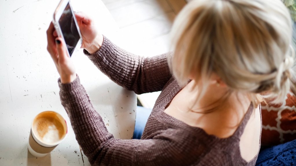 A woman checking a business website on her phone at a cafe table